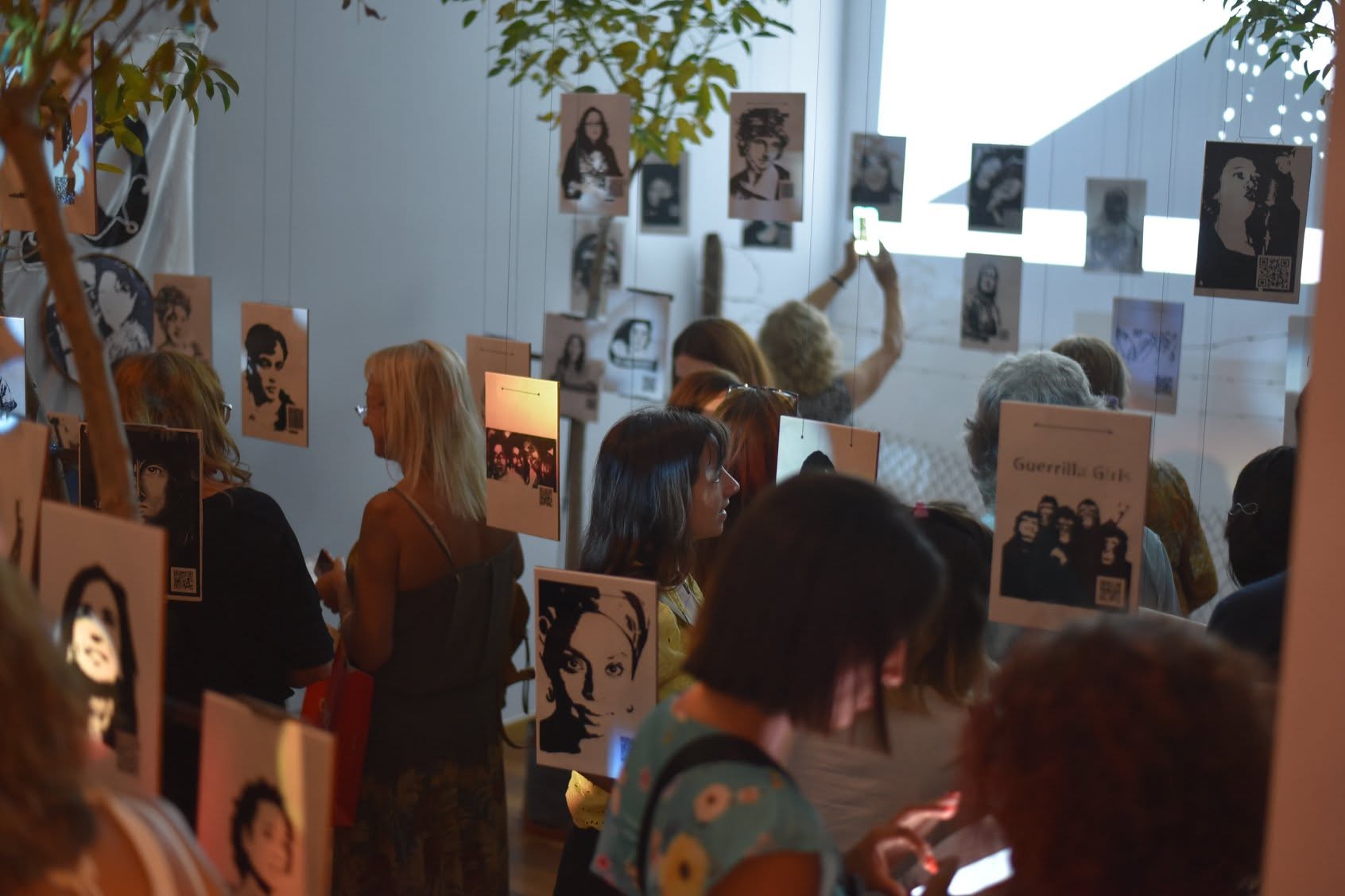 Visitors moving through suspended portraits at the CCK opening